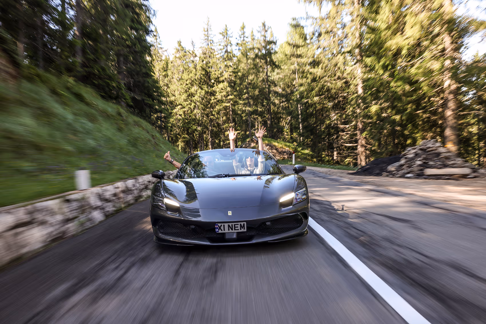 Front view of Ferrari 296 GTB on a Supercar Driver tour, with driver and passenger raising their arms in excitement during the supercar adventure.
